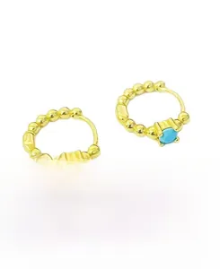 Détail macro de boucles d'oreilles créoles perlées en argent S925 doré et zircon bleu clair