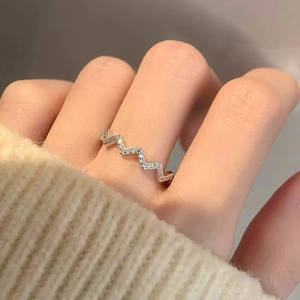 Gros plan d'une bague en argent S925 ondulée avec cristaux pavés sur fond tricoté