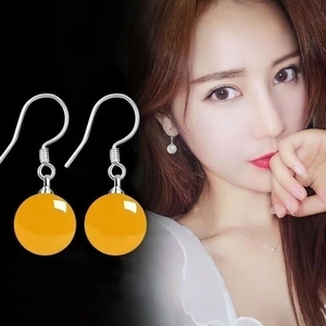Detail view of ethnic S925 silver earrings with round yellow agate beads on a model