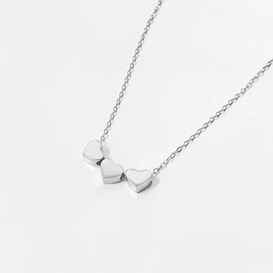 Detailed view of three solid silver heart pendants on a minimalist sterling silver chain