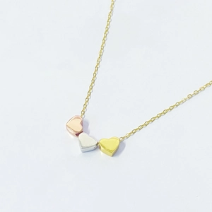 Detail of three-tone S925 silver heart pendants in rose gold, silver and gold finish