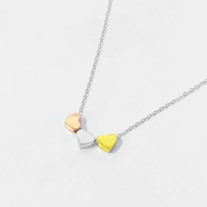 Close-up of three sliding heart pendants in rose gold, silver, and yellow gold finish