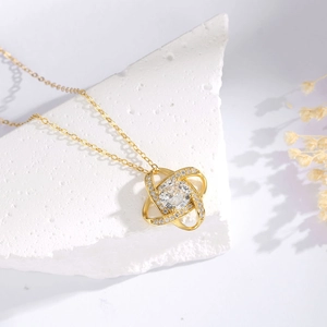 Detail of gold clover necklace with sparkling micro-pave diamonds on stone background