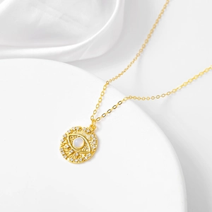 Detail of gold evil eye pendant with moonstone and cubic zirconia on silk background