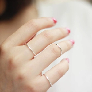 Detailed close-up of three minimalist thin silver stackable rings worn on female fingers