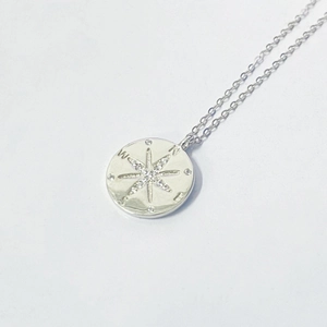 Detailed view of S925 sterling silver compass pendant with crystal pavé starburst