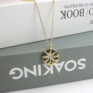 Macro view of gold S925 silver compass pendant with starburst and N S E W engravings