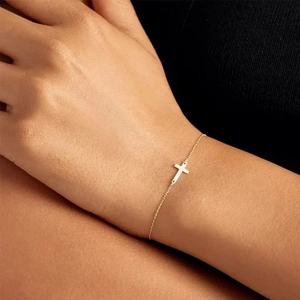 Elegant gold S925 sterling silver cross pendant bracelet on model wrist with thin chain