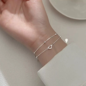 Close-up of a double-layer S925 sterling silver heart bracelet on a woman's wrist