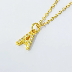 Detailed close-up of a gold-plated necklace with a sparkling zircon-encrusted letter A