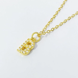 Macro detail of gold plated letter B pendant necklace with pave cubic zirconia crystals