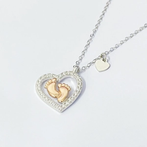 Detailed close-up of S925 silver heart necklace featuring rose gold baby footprints and zircons