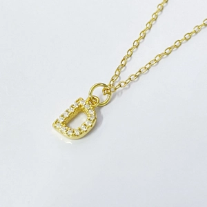 Detailed shot of S925 silver gold letter D pendant with cubic zirconia stones