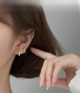 Close-up of gold-plated S925 silver hoop earrings with pavé set white zirconias on ear