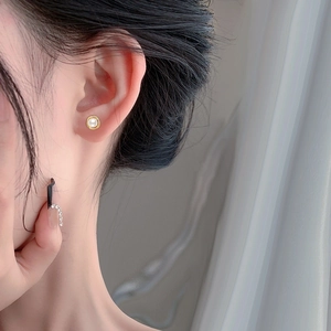 Elegant S925 silver pearl stud earrings with gold rim worn by a model for a refined look