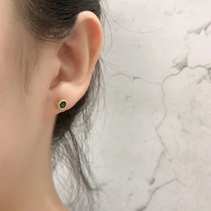 Vintage gold stud earrings with green zircon stones shown on ear for minimalist style