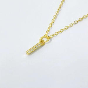 Detailed macro of gold letter pendant necklace with shimmering zircon stones on white background