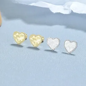 Détail de boucles d'oreilles cœur en argent 925 avec texture martelée dorée et argentée