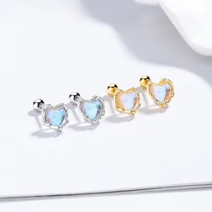 Close-up of heart-shaped moonstone stud earrings with silver and gold screw ball backs