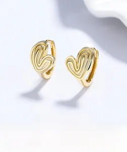 Macro view of gold striped heart-shaped S925 sterling silver earrings texture