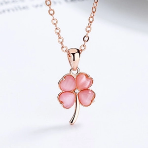 Macro shot of pink heart-shaped cat-eye stone clover pendant with rose gold chain