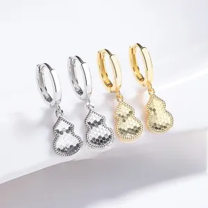 Detailed view of silver and gold 925 sterling silver gourd hoop earrings on a magazine