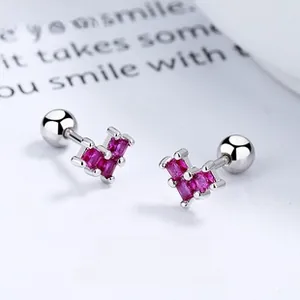 Macro shot of red heart stud earrings with silver screw ball backings on paper