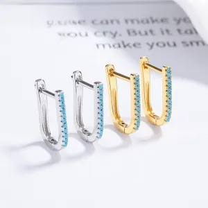 Detail view of U-shaped gold and silver earrings with turquoise stones on a vintage card