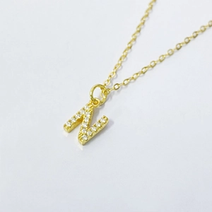 Detailed macro shot of a gold-plated letter N pendant necklace with micro-pave zircons
