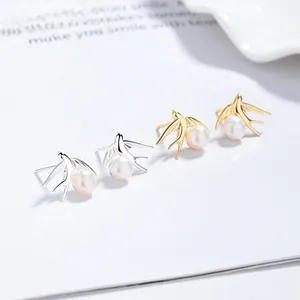 Detailed macro view of swallow stud earrings with pearls in silver and gold finishes