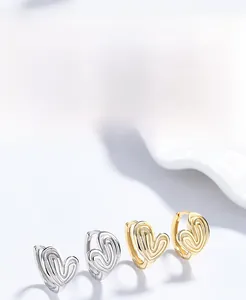 Macro detail of textured heart-shaped S925 sterling silver hoop earrings in silver and gold