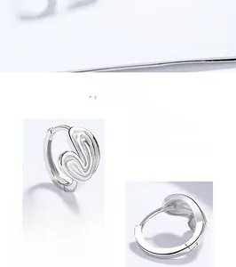 Macro detail of 925 sterling silver heart hoop earrings with polished finish on white back