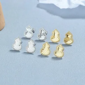 Detailed macro view of gold and silver gourd stud earrings with intricate honeycomb texture