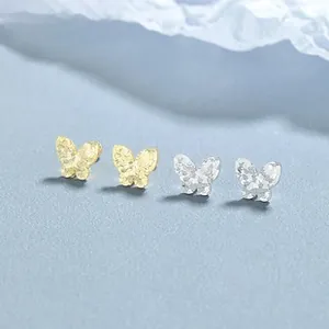 Gros plan de boucles d'oreilles papillon dorées et argentées à texture martelée