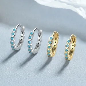 Detailed close-up of 925 silver and gold turquoise hoop earrings on a textured background