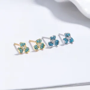 Detailed macro of floral earrings with blue enamel petals and sparkling center diamonds