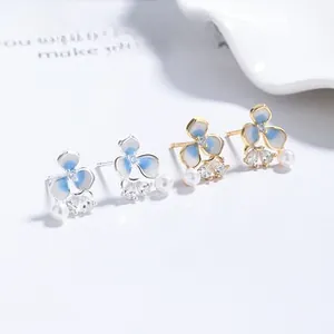 Macro detail of cross flower earrings with blue enamel petals and sparkling cubic zirconia
