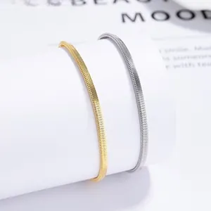 Detailed close-up of polished gold and silver flat snake chains on a white pedestal