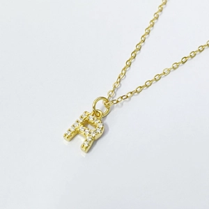 Macro detail of gold-plated letter R pendant necklace with paved zircon stones