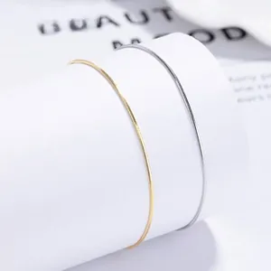 Detail of minimalist 925 sterling silver and gold snake bone bracelets on a white stand