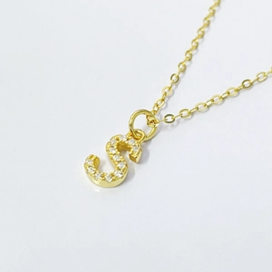 Macro detail of gold S letter pendant necklace with pavé cubic zirconia setting