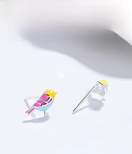 Detail of 999 sterling silver bird earrings featuring vibrant yellow pink and blue enamel