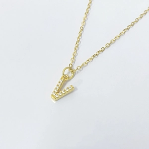 Macro view of gold initial V pendant with sparkling zircons on a delicate chain necklace