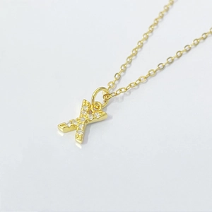 Macro shot of gold X-letter pendant with pavé cubic zirconia on O-chain necklace