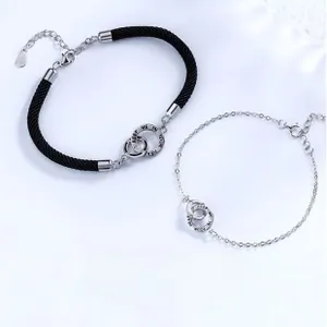 Detail of interlocking Möbius rings on black braided cord and silver chain bracelets