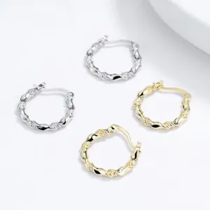 Detailed view of silver and gold twisted rope hoop earrings on light grey background