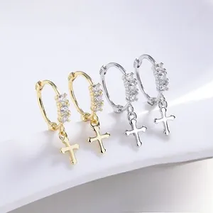 Macro detail of S925 sterling silver hoop earrings with zircon cross pendants in gold and silver
