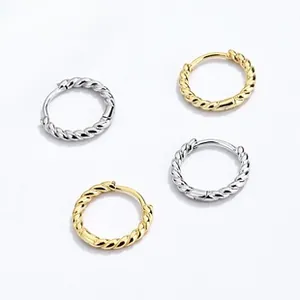 Detail of twisted hoop earrings in gold and silver finish with textured spiral design