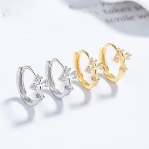 Close-up of cross hoop earrings with inlaid zircons in silver and gold finishes