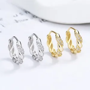 Macro shot of silver and gold twisted hoop earrings with delicate cubic zirconia inlay